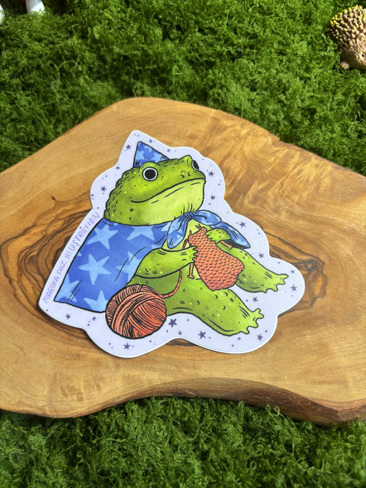 Frog wizard vinyl sticker knitting with orange yarn in starry hat and cape