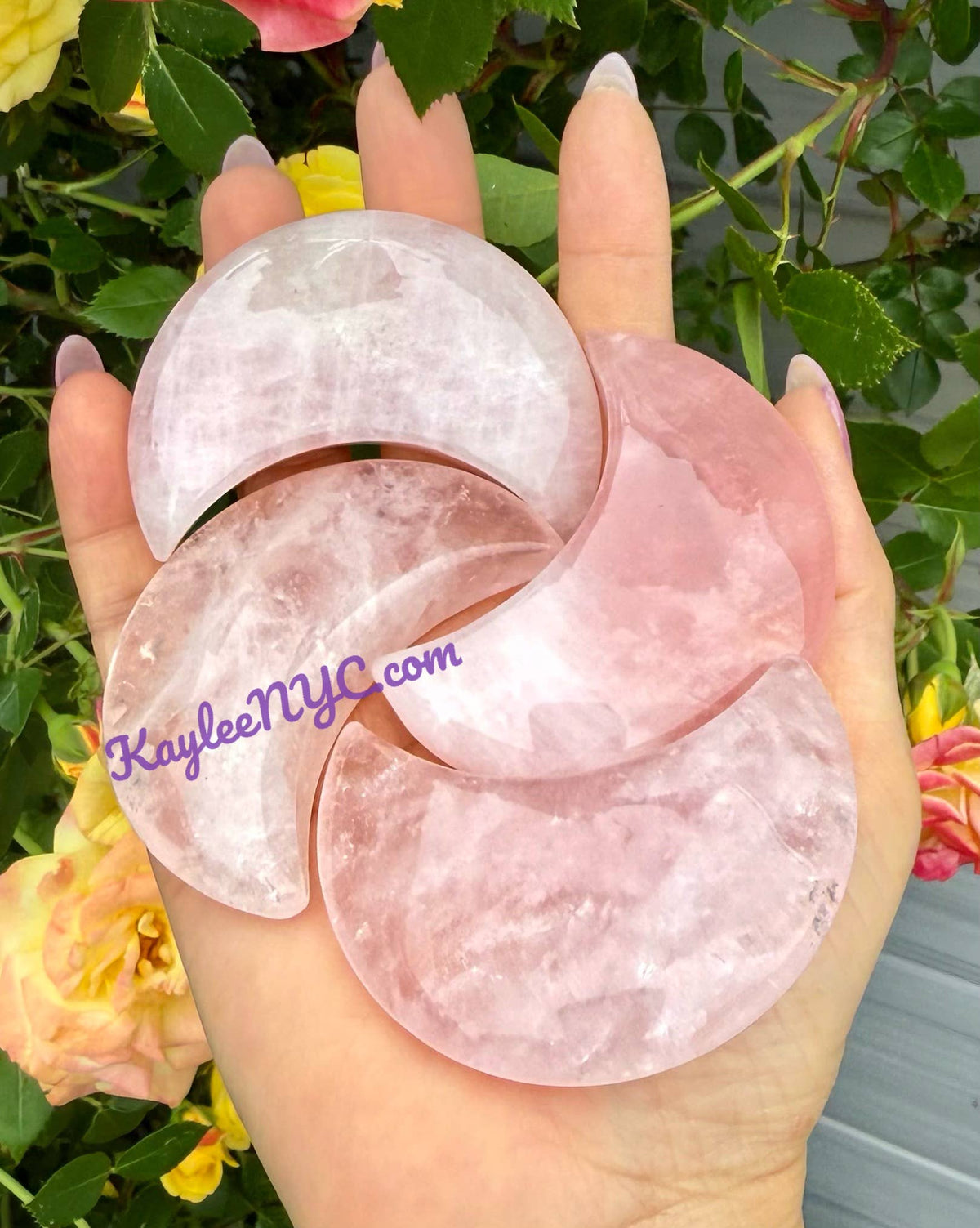 Polished natural rose quartz crescent moon crystals held in hand